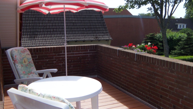 Dachgeschosswohnung mit grosser Südterrasse mit Gartenmöbel und Sonnenschirm.