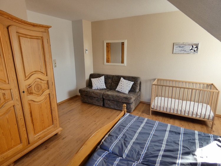 Blick in das Schlafzimmer 1 mit Kleiderschrank und Baby-/Kleinkindbett.
