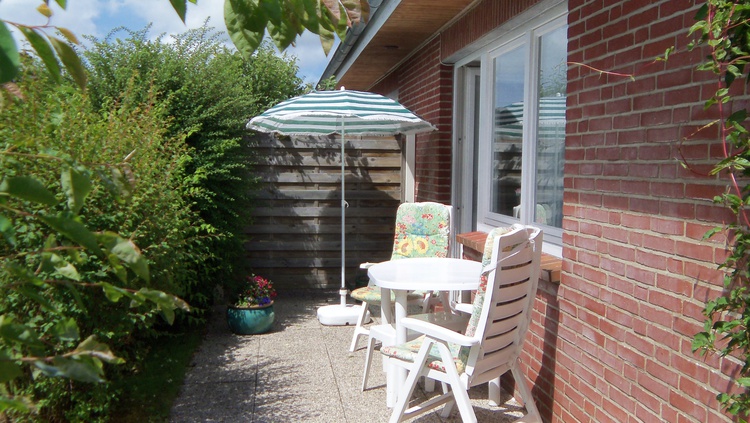 Südterrasse mit Gartenmöbel mit Auflagen und Sonnenschirm in Südlage.
